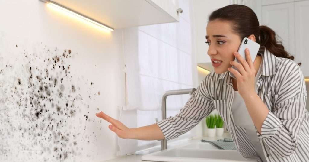 Femme parlant au téléphone et regardant le mur touché dans la cuisine